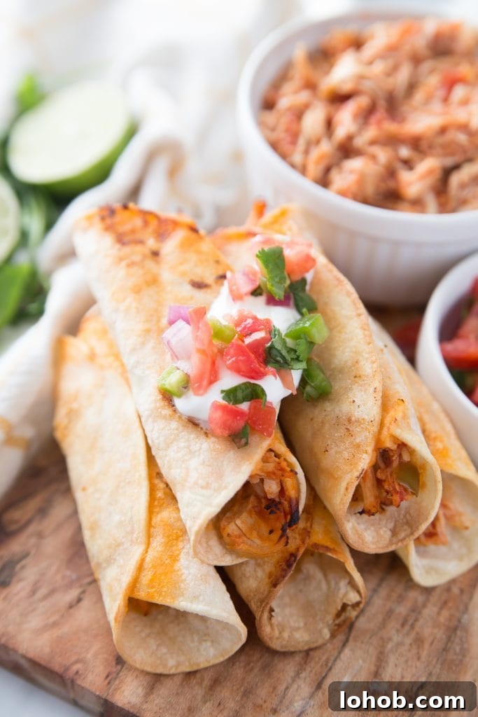 Top Weight Watchers Chicken Recipes: Quick Low-Point Meals 6 Five chicken taquitos with toppings are stacked in a pyramid on a cutting board- extra salsa lime chicken is in a white bowl in the background