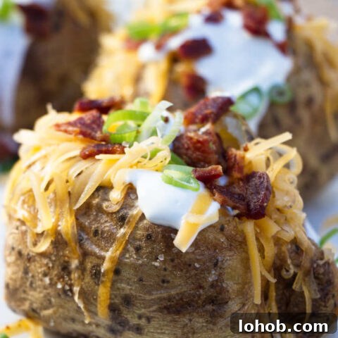 4 air fryer baked potatoes topped with sour cream, cheese, bacon and onions
