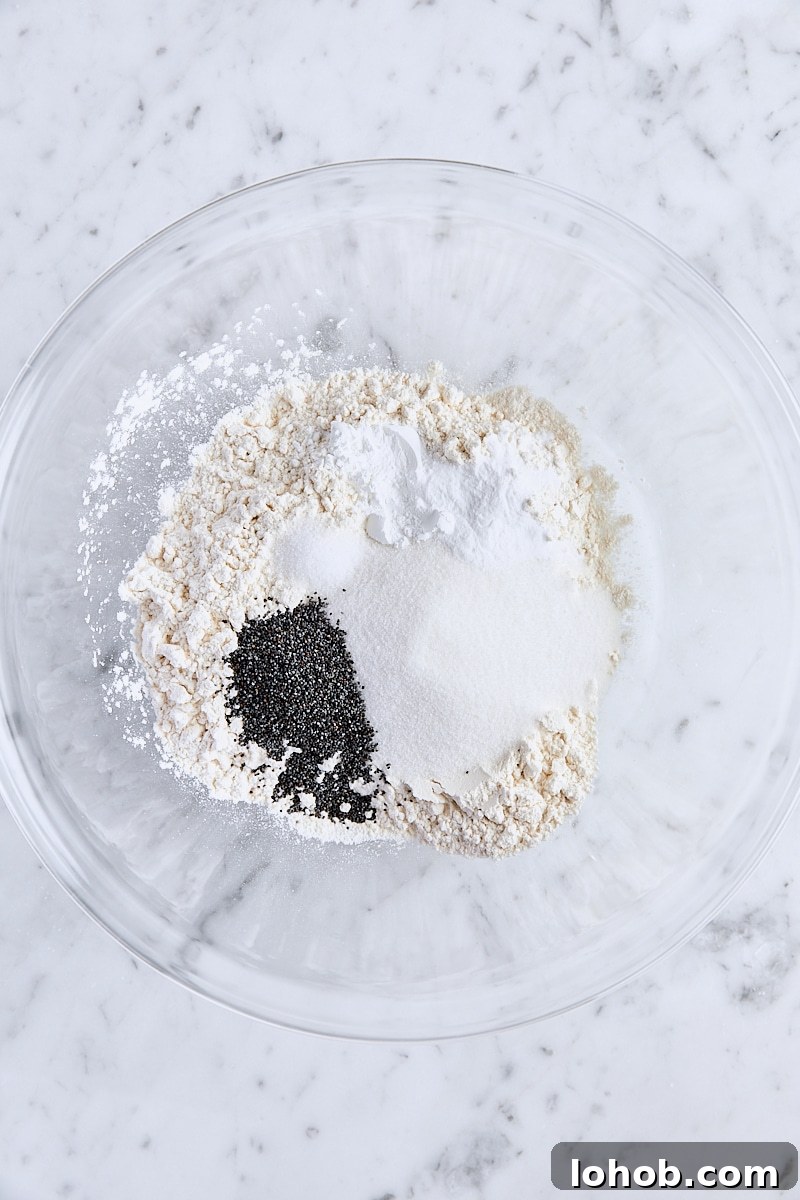 Lemon Poppy Seed Muffins Recipe — Moist, Zesty Morning Treat 4 All-purpose flour, granulated sugar, poppy seeds, baking powder, baking soda, and salt in glass bowl