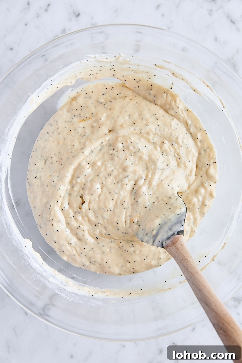 Lemon Poppy Seed Muffins Recipe — Moist, Zesty Morning Treat 9 Lemon poppy seed muffin batter in large glass bowl with spatula