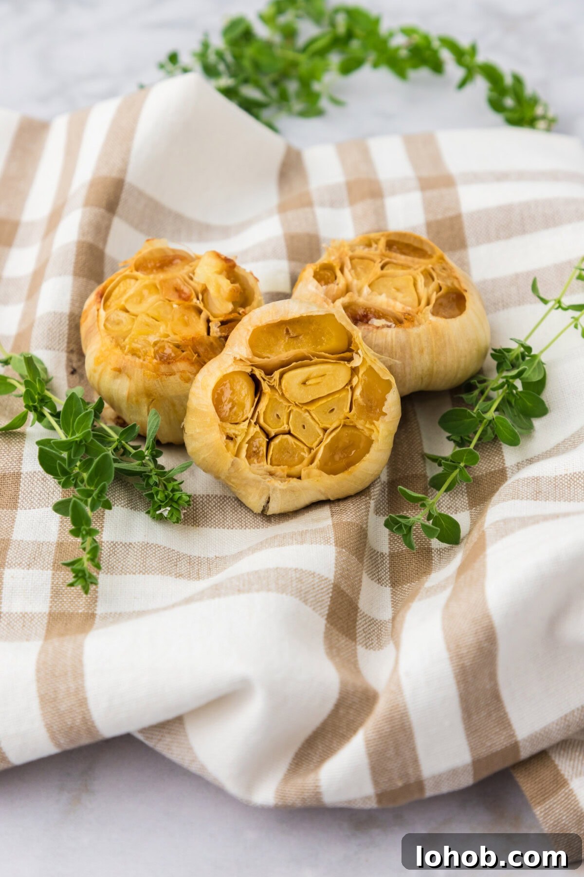 Three bulbs of roasted garlic on a towel