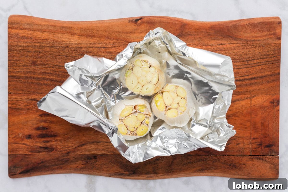 sliced whole bulbs of garlic in aluminum foil