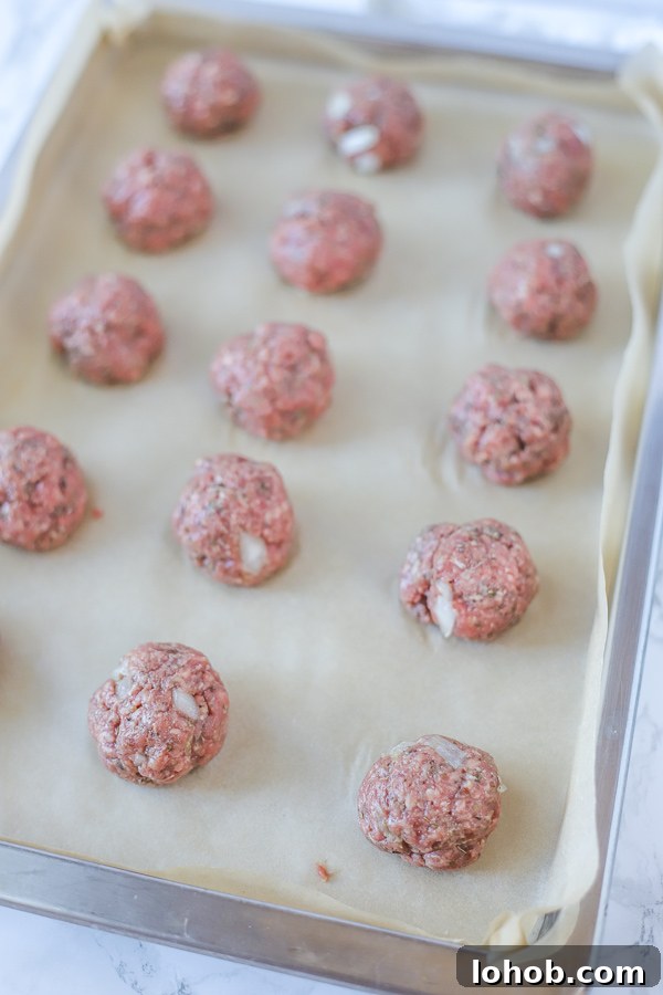 raw gluten free meatballs on a parchment paper lined baking sheet