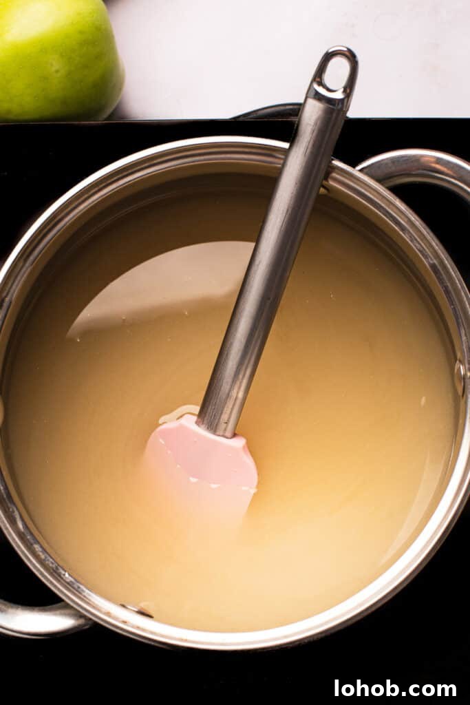 A saucepan of undyed sugar candy mixture with a spatula resting in it.
