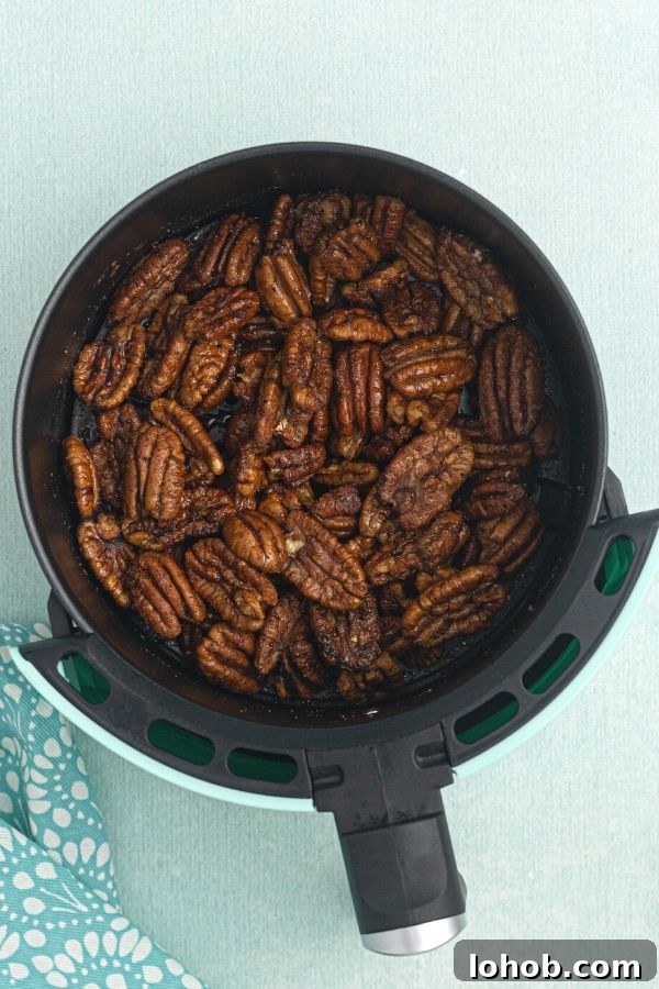Crispy Spiced Pecans Made in the Air Fryer 5 Spiced air fryer pecans, after being cooked in the air fryer, resting in the air fryer basket.