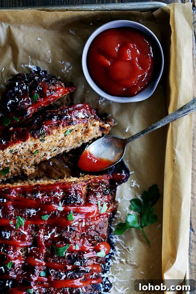 This turkey meatloaf takes just 10 minutes to prepare; seasoned with Parmesan cheese, oregano, basil and garlic. An overhead view of slices of Turkey Meatloaf with a bowl of ketchup and a spoon.