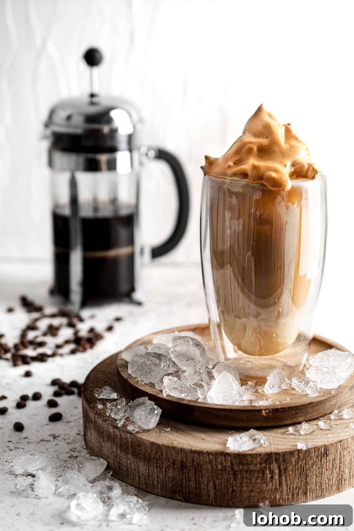 Vietnamese Iced Coffee with Condensed Milk (Cà Phê Sữa Đá) 2 Tall glass of iced coffee on a wooden board, topped with Dalgona foam