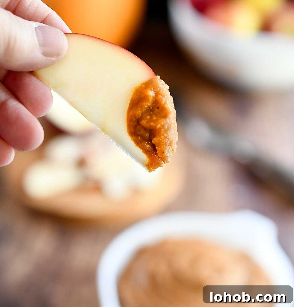 An apple slice dipped into the pumpkin dessert hummus.
