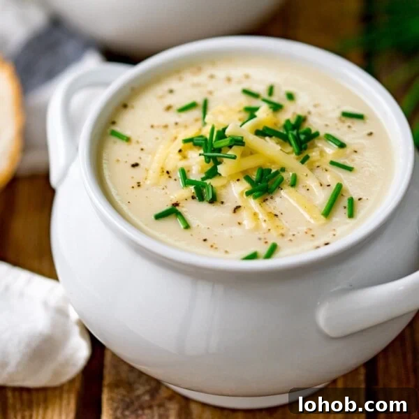 Smoky Roasted Cauliflower Salad with Garlic Lemon Dressing 10 Close up of a white bowl filled with cauliflower soup and topped with chopped chives, grated cheese and black pepper