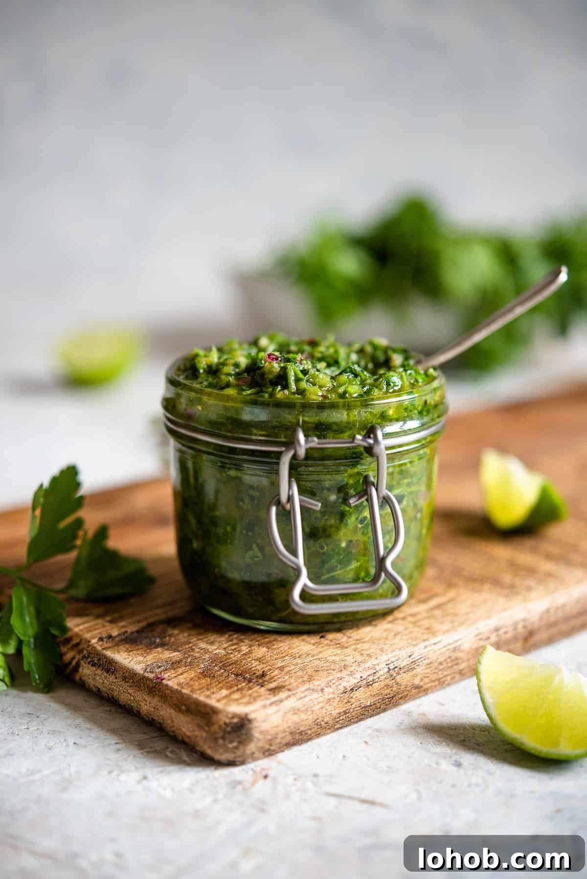 A mason jar filled with Cilantro Chimichurri on a wood board.